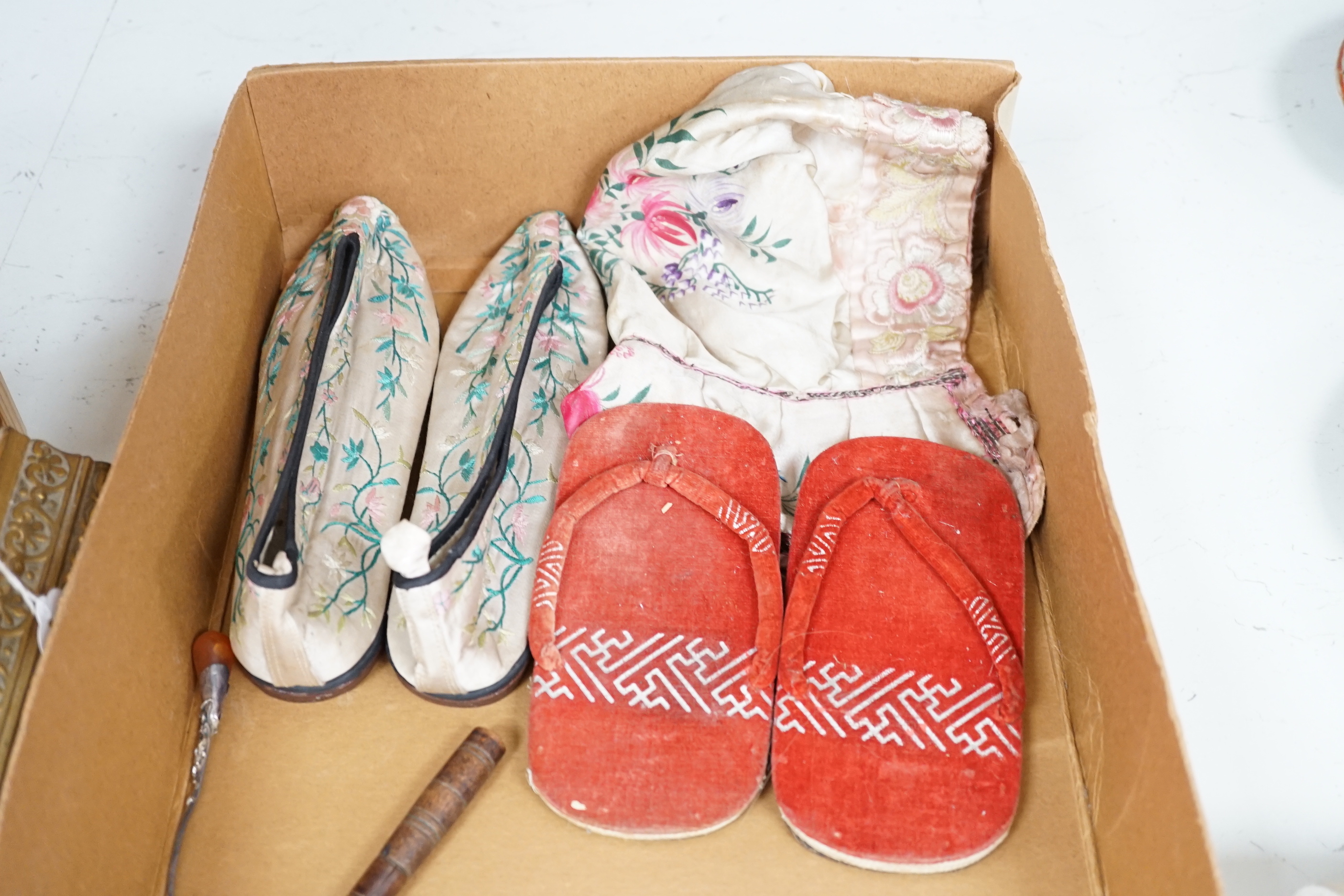 Two Chinese Papier mache dolls with embroidered silk clothing, a pair of Chinese embroidered silk slippers, a similar child’s bonnet a pair of Japanese slippers and three other dolls